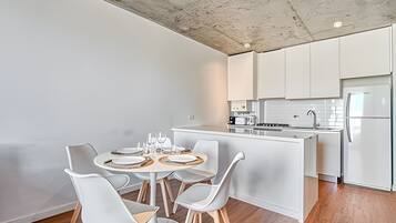 Una cocina moderna con armarios blancos, una isla central y un comedor con sillas blancas.