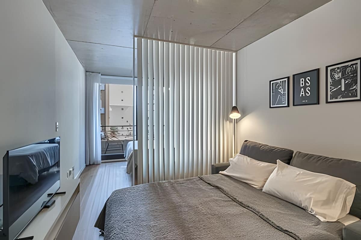 Een moderne slaapkamer met een bed, televisie, lamp en balkon uitzicht.