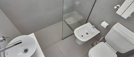 A modern bathroom with a sink, bidet, toilet, and glass shower enclosure.