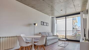A modern living room with a dining area, large windows, and a view of the city.