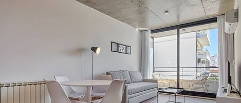 Uma sala de estar moderna com área de jantar, janelas amplas e vista para a cidade.