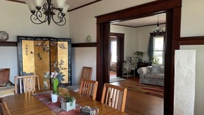 A dining area with a wooden table, chairs, a chandelier, and a traditional decorative screen. - Relax Inn The Grove (Forest Grove)