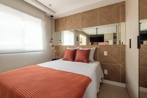 Une chambre d’hôtel moderne avec un grand lit, un miroir et un mur orné d’un motif géométrique.