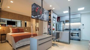 A modern bedroom with a bed, bedside table, and a TV mounted on the wall. - Charming Studio - GRU 2001 (Jardim Flor da Montanha Guarulhos)