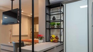 A modern kitchen with a built-in island, a black-framed mirror, and a white refrigerator. - Charming Studio - GRU 2001 (Jardim Flor da Montanha Guarulhos)