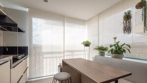 A modern kitchen with a central island, bar stools, and potted plants. - Charming Studio - GRU 2001 (Jardim Flor da Montanha Guarulhos)