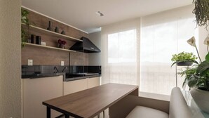 A modern kitchen with a wooden table, black cabinets, and a window with a view. - Charming Studio - GRU 2001 (Jardim Flor da Montanha Guarulhos)