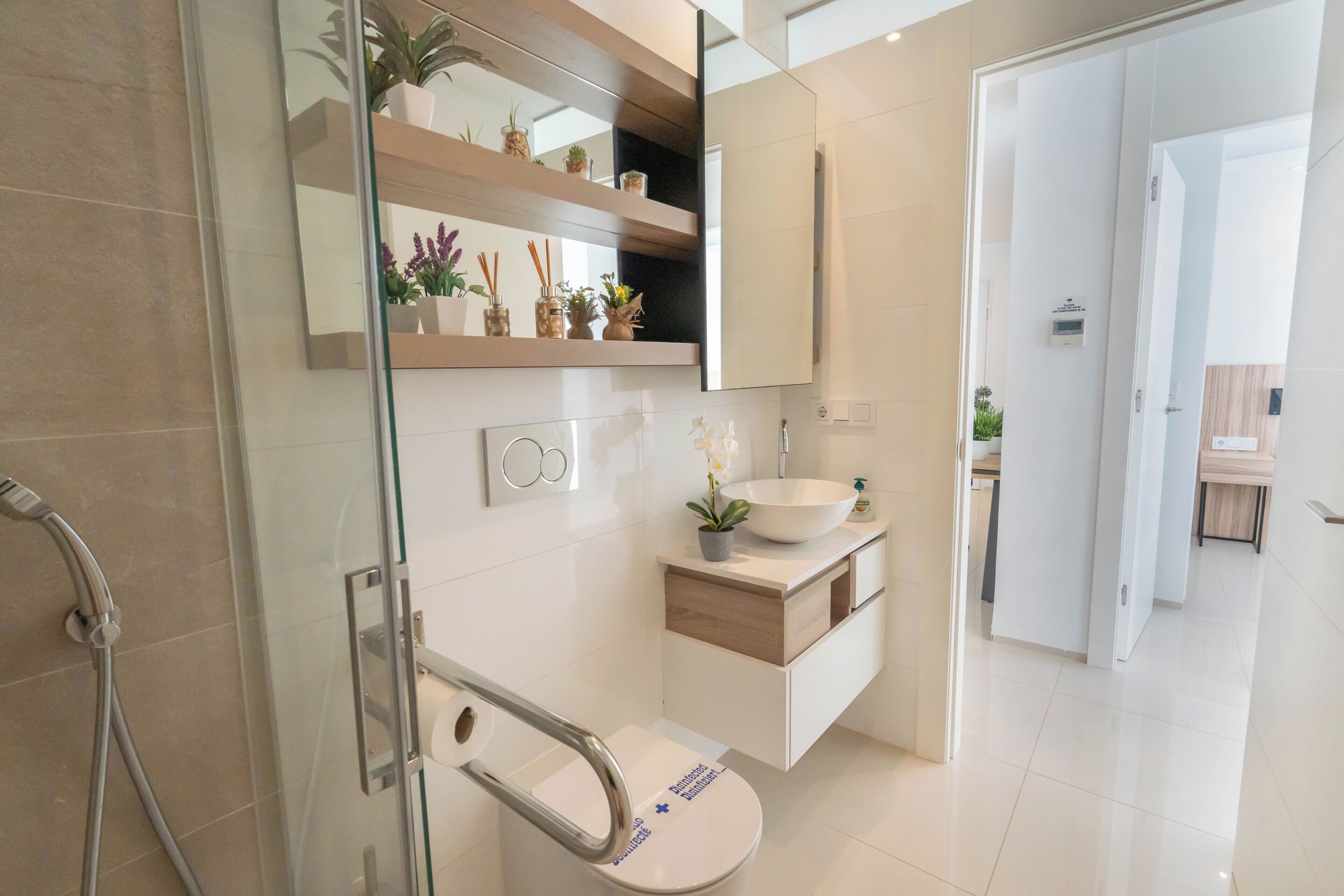A modern bathroom with a glass shower enclosure, a white sink, and a mirror above the vanity.