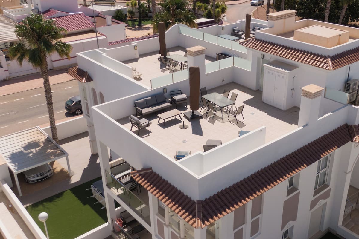 A multi-story building with outdoor terraces, including a dining area with tables and chairs, and a pool area.