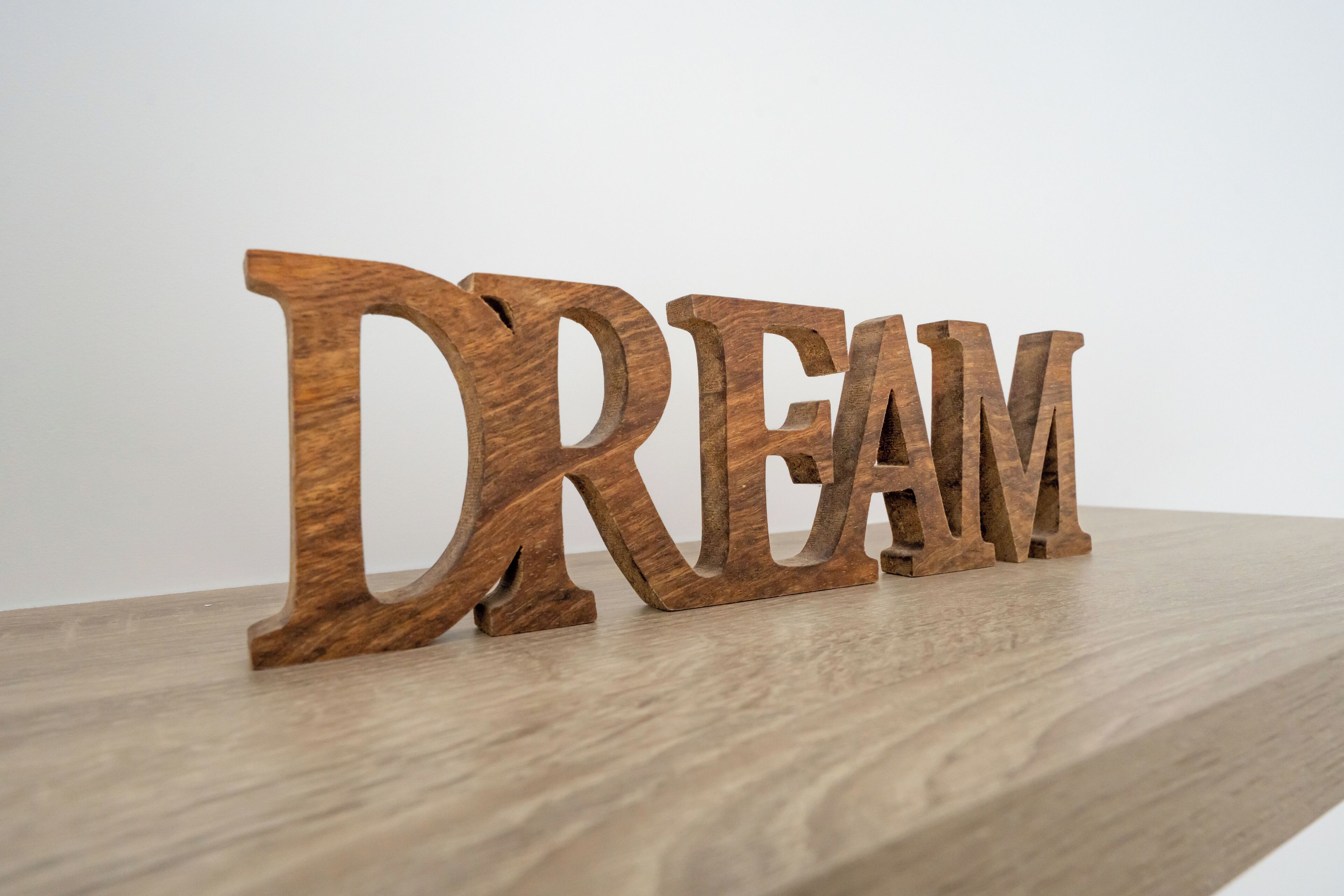 Wooden letters spelling "DREAM" on a wooden surface.