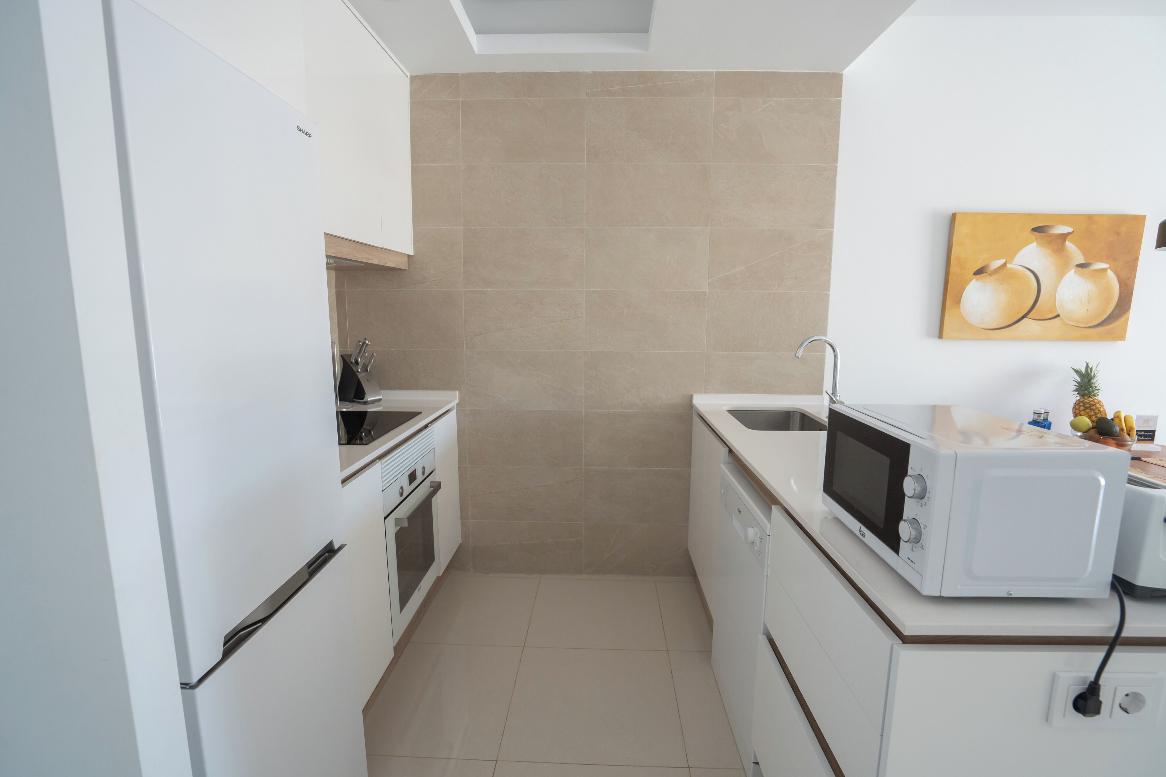 A compact kitchen with white cabinets, a microwave, a sink, and a stove.