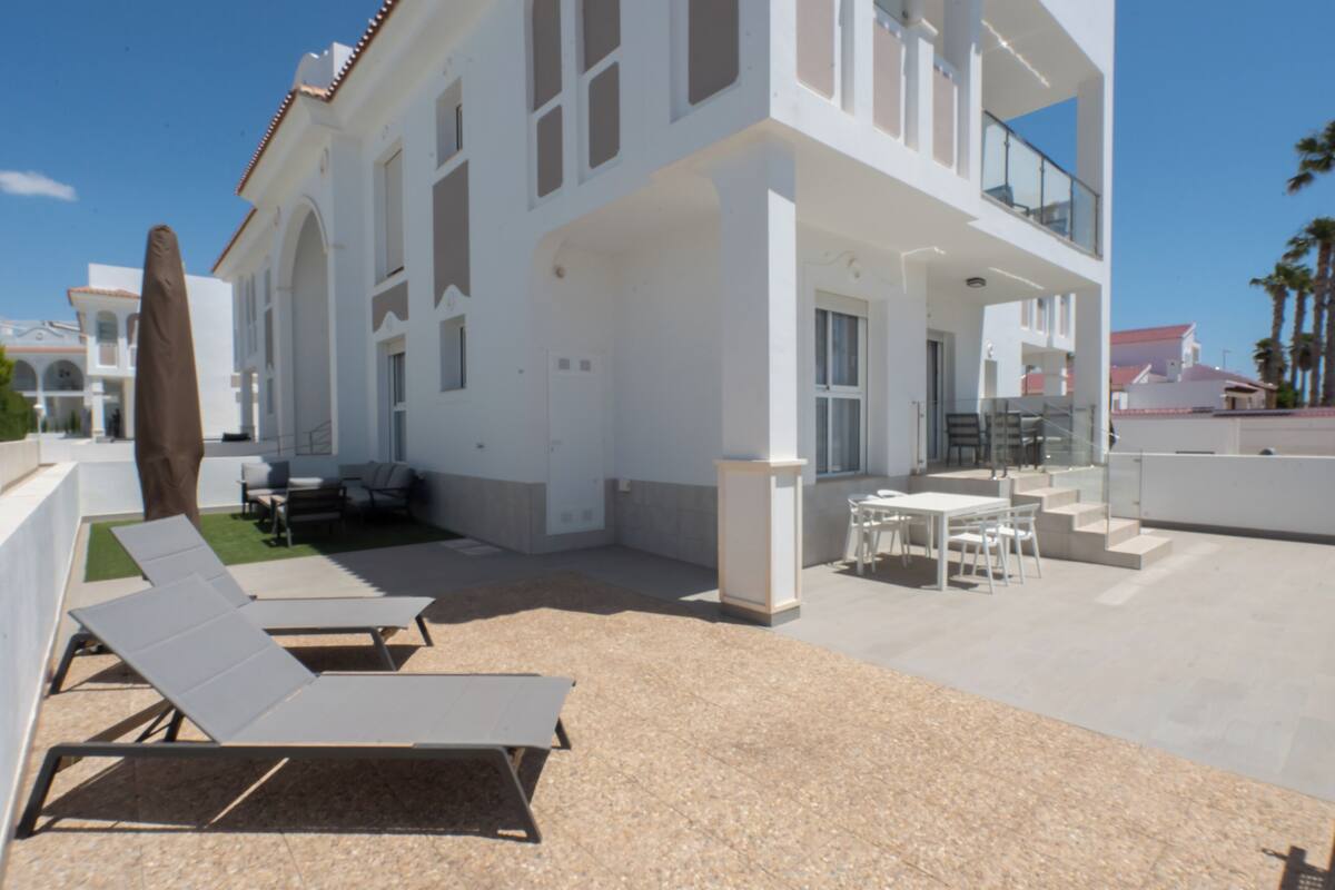 A modern building with a balcony, outdoor seating, and a pool area.