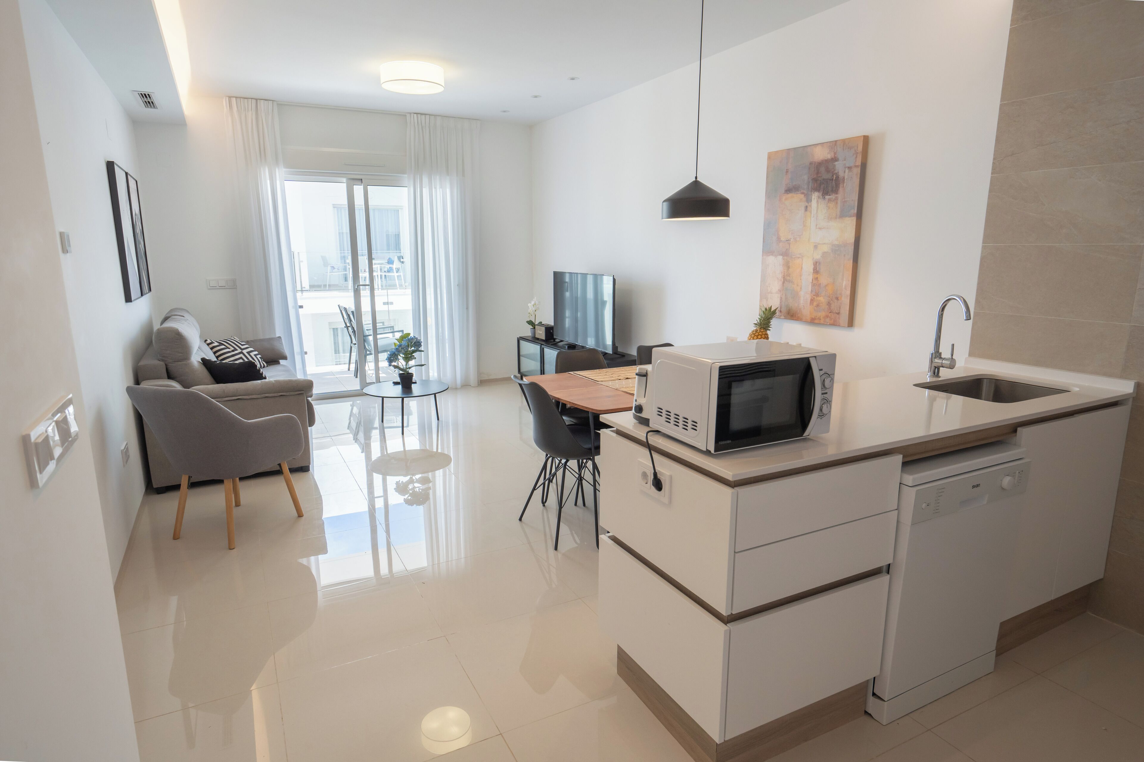 A modern kitchen with a microwave, dishwasher, and a dining area with a table and chairs.
