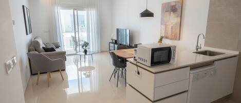 A modern kitchen with a microwave, dishwasher, and a dining area with a table and chairs.