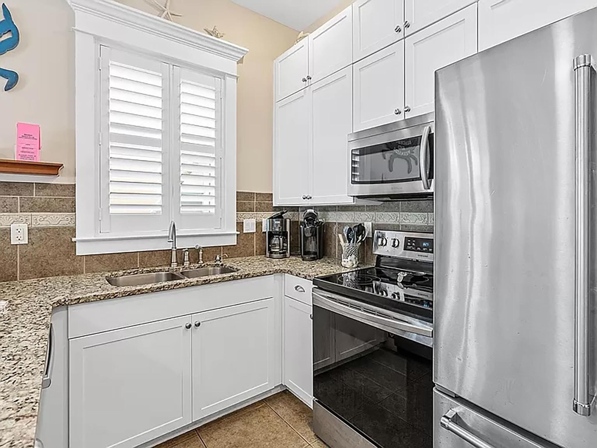 A kitchen with white cabinets, a stainless steel refrigerator, a microwave, and an oven.