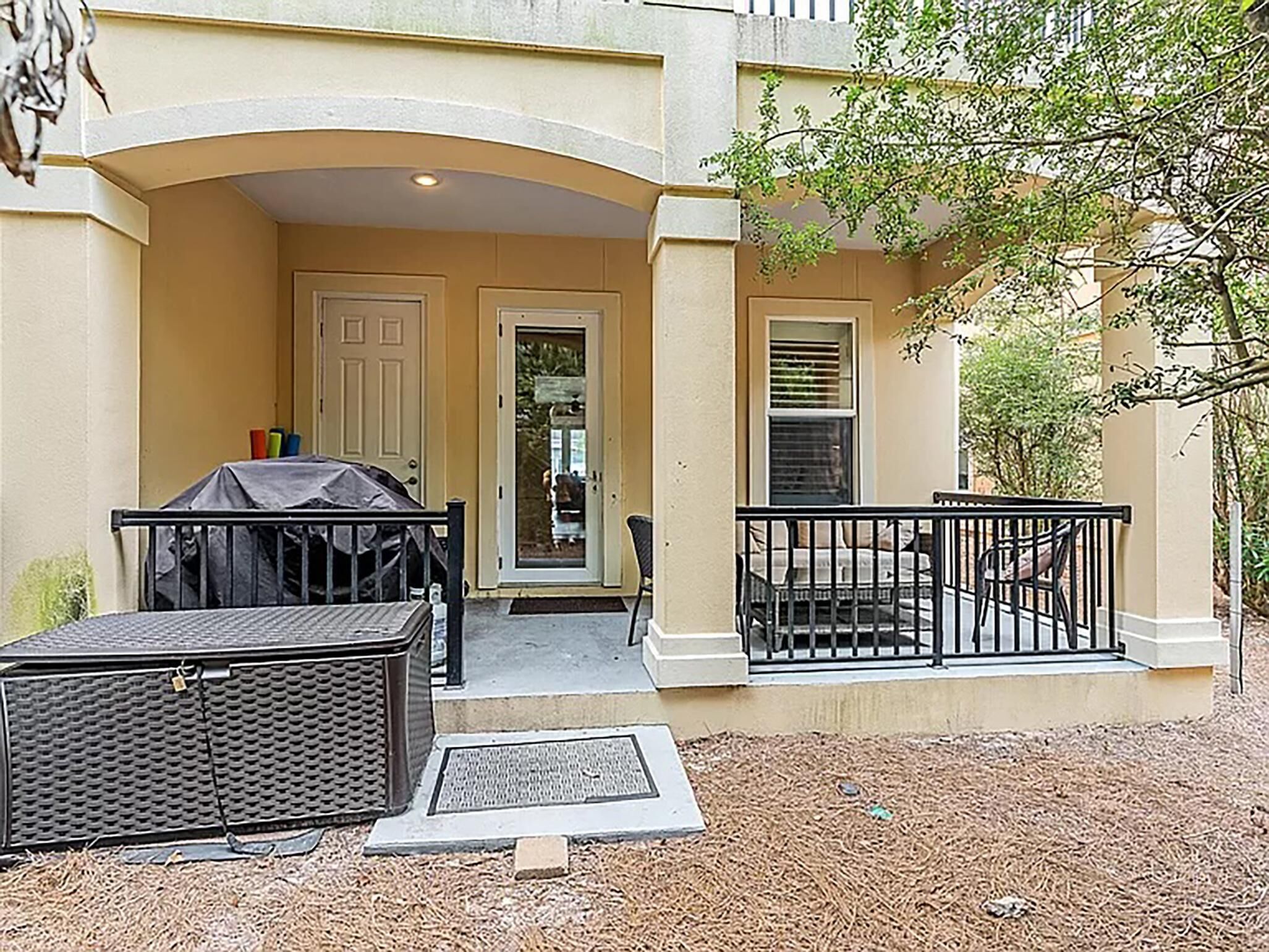 An outdoor patio area with a covered seating area, a grill, and a small table.