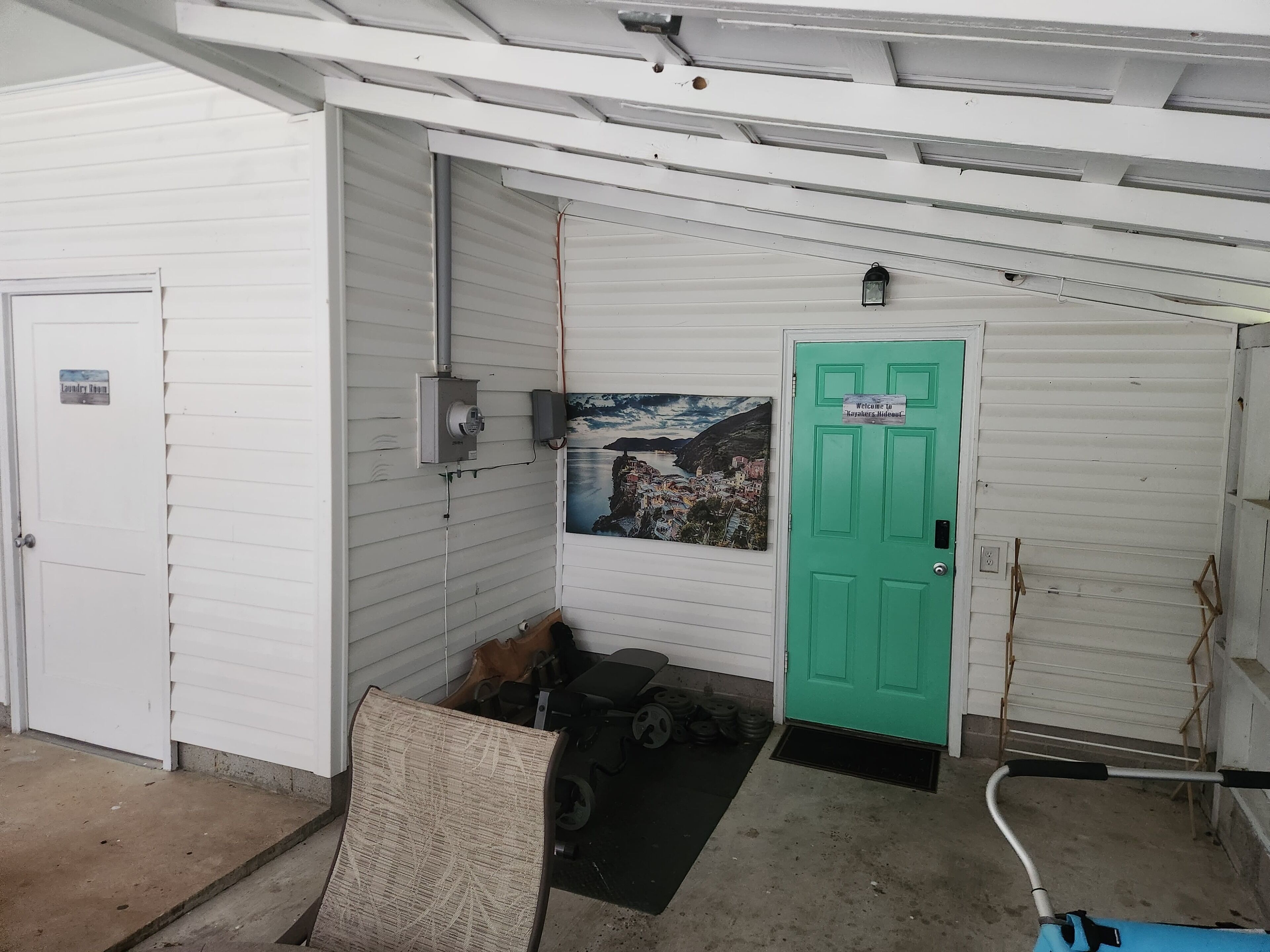 A garage with a green door, a welcome sign, a mounted picture, and a tire rack.