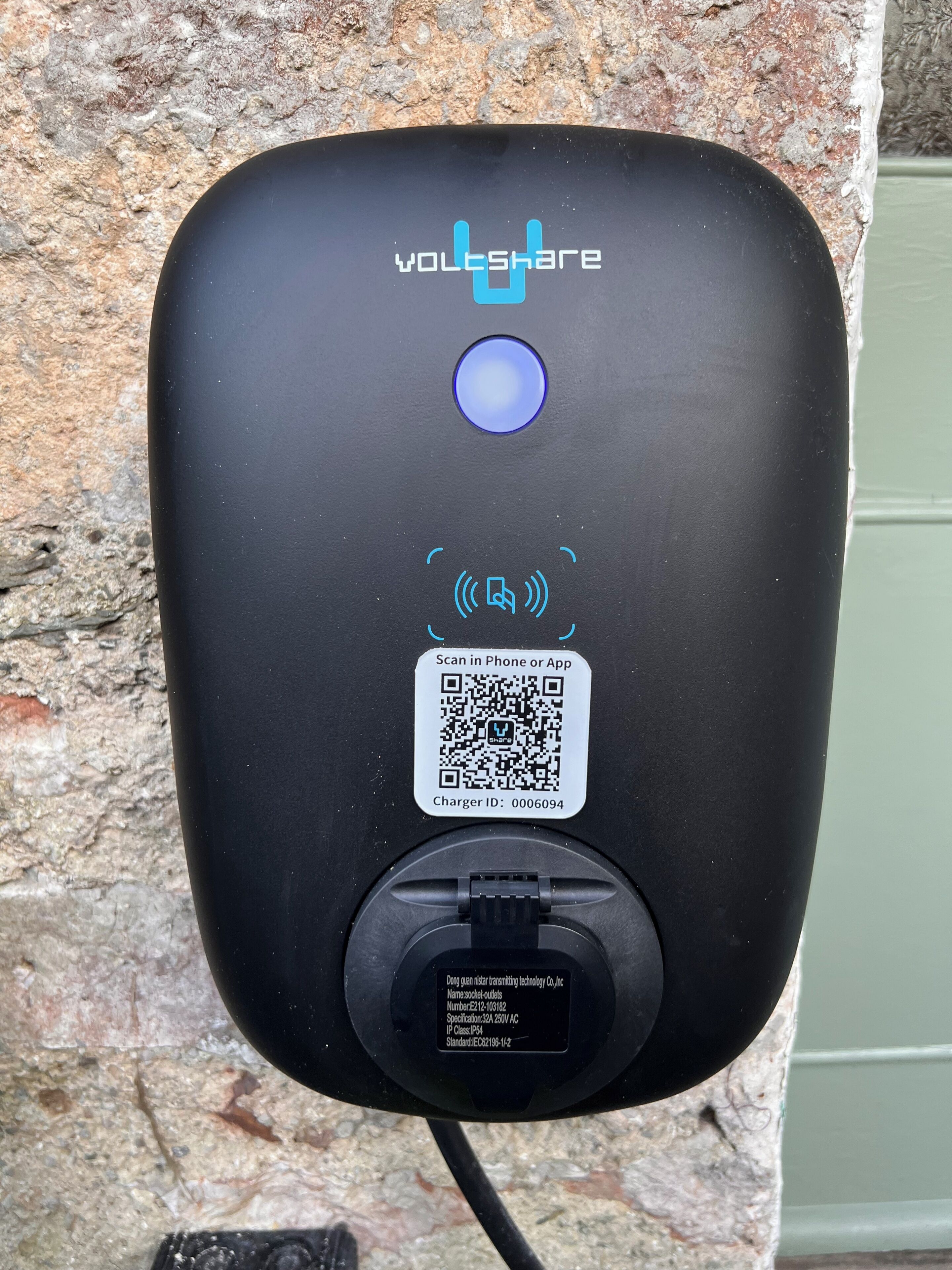 A black VOLTSHARE charging station with a QR code and a blue light indicator.