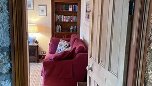Ett mysigt vardagsrum med en röd soffa, en bokhylla i trä och en rutig matta.