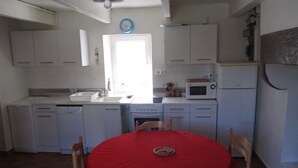 Une cuisine de taille réduite avec des meubles blancs, un four à micro-ondes, un évier et une table à manger avec des chaises.