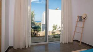 A room with a sliding glass door leading to a balcony with a view of the sea. - Villa Kassandra (Pitsidia)