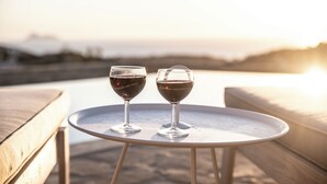 Two wine glasses on a round table with a view of the sunset in the background. - Villa Kassandra (Pitsidia)