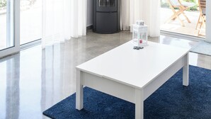 A modern living room with a white table, a black fireplace, and a ceiling fan. - Villa Kassandra (Pitsidia)