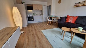 Ein kompakter Wohnbereich mit Küchenzeile, Essbereich und einer Sitzecke mit Sofa und Tischen.