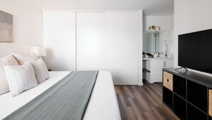 A modern bedroom with a bed, a TV, and a wardrobe.