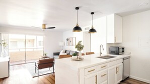 A modern kitchen with a large island, white cabinetry, and pendant lighting.