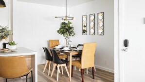 A dining area with a wooden table, black and yellow chairs, a hanging light fixture, and wall-mounted mirrors.