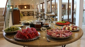 Una mesa de buffet con diversas opciones de comida, como frutas, carnes y salsas.