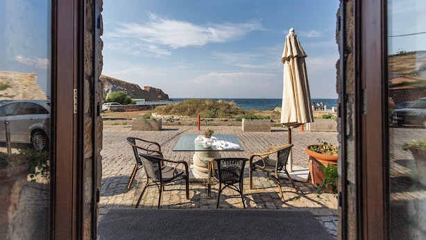 Un espacio al aire libre con mesas y sillas, una planta en maceta y vistas al mar y acantilados.