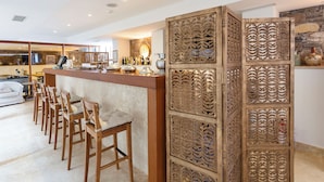 Una cocina moderna con barra, sillas de madera y un separador decorativo.