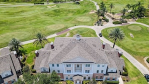 A large, two-story building with a symmetrical facade, surrounded by well-maintained lawns and palm trees. - Reunion Charming Disney & Star Wars Themed Home (Kissimmee)