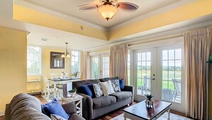 A spacious living room with a large sofa, a coffee table, and a dining area in the background. - Reunion Charming Disney & Star Wars Themed Home (Kissimmee)
