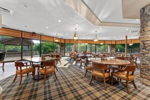 Enjoy meals in this dining area with wooden tables and chairs, surrounded by large windows offering views of the surrounding greenery.