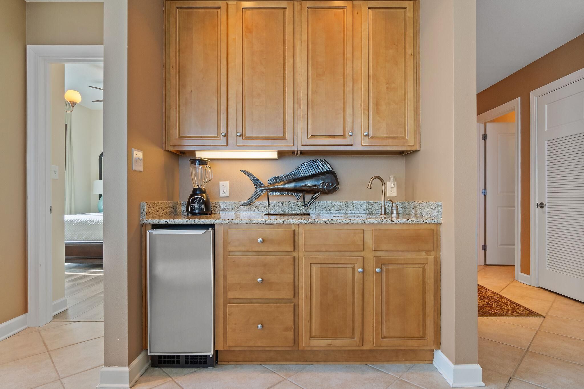 A kitchen with wooden cabinets, a built-in fish sculpture, a blender, and a refrigerator.