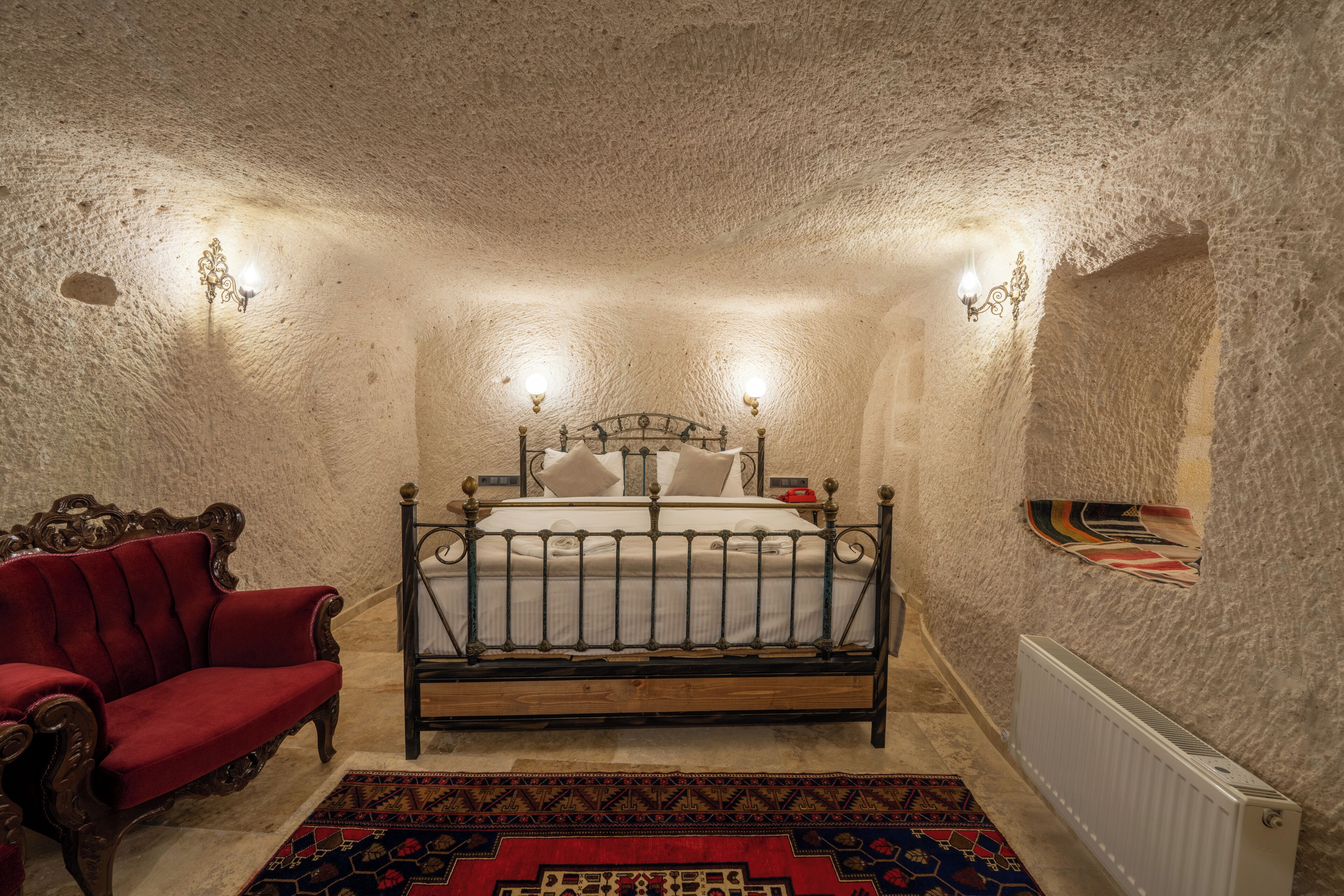A bedroom with a bed, a red armchair, and a patterned rug.