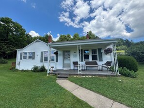 A white two-story house with a porch, a number '1830' sign, and a small garden. - Farmhouse with amazing views, enjoy the peacefulness of living on a farm (Crumpler)