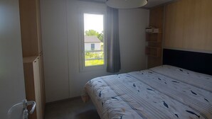 Ein Schlafzimmer mit Bett, Fenster, Deckenlampe und Kleiderschrank.