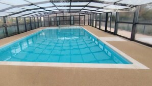 Ein Innenpool mit Glasdach, umgeben von Wänden mit Fenstern.