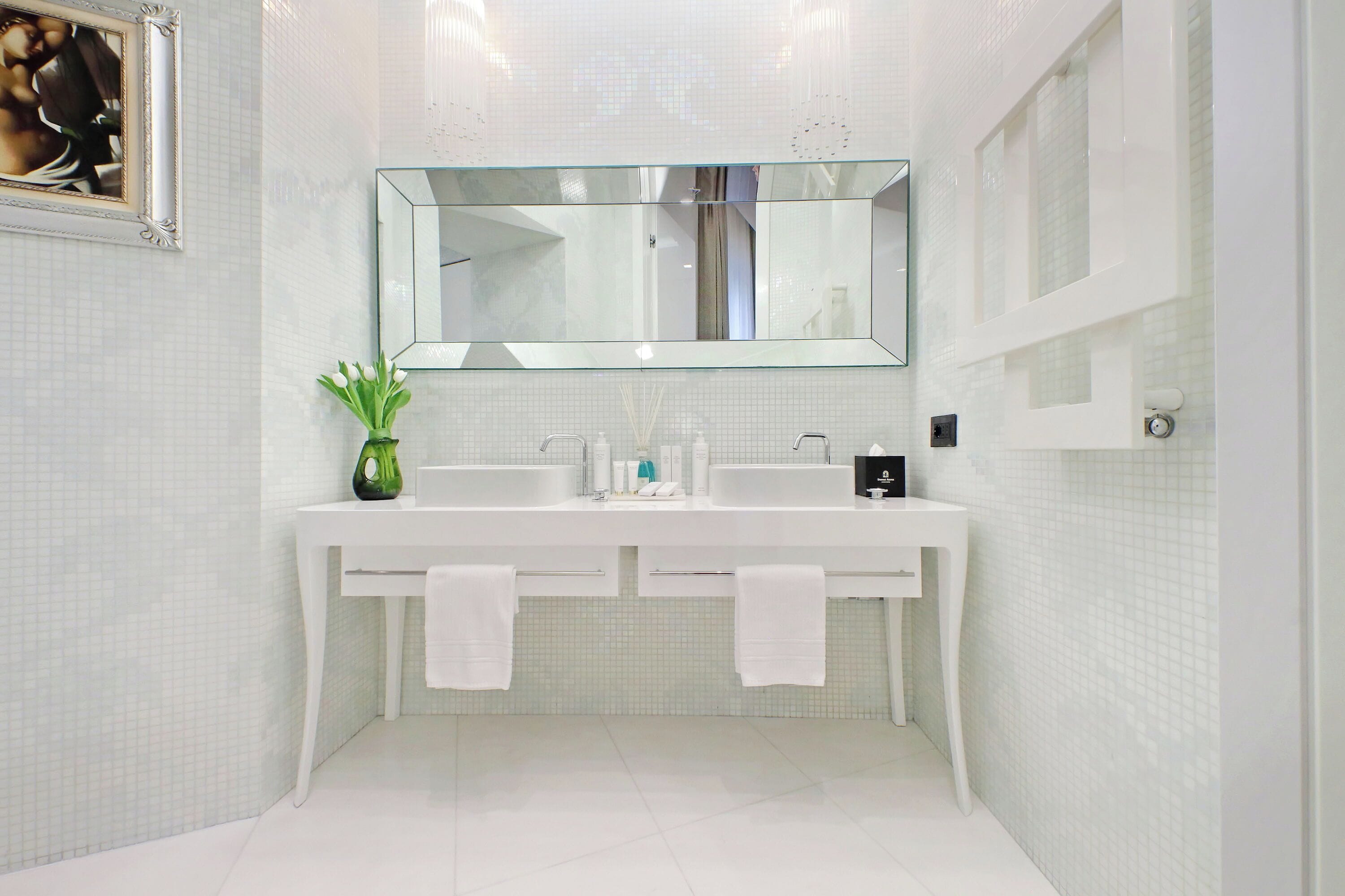 A modern bathroom with two sinks, a large mirror, and a potted plant.