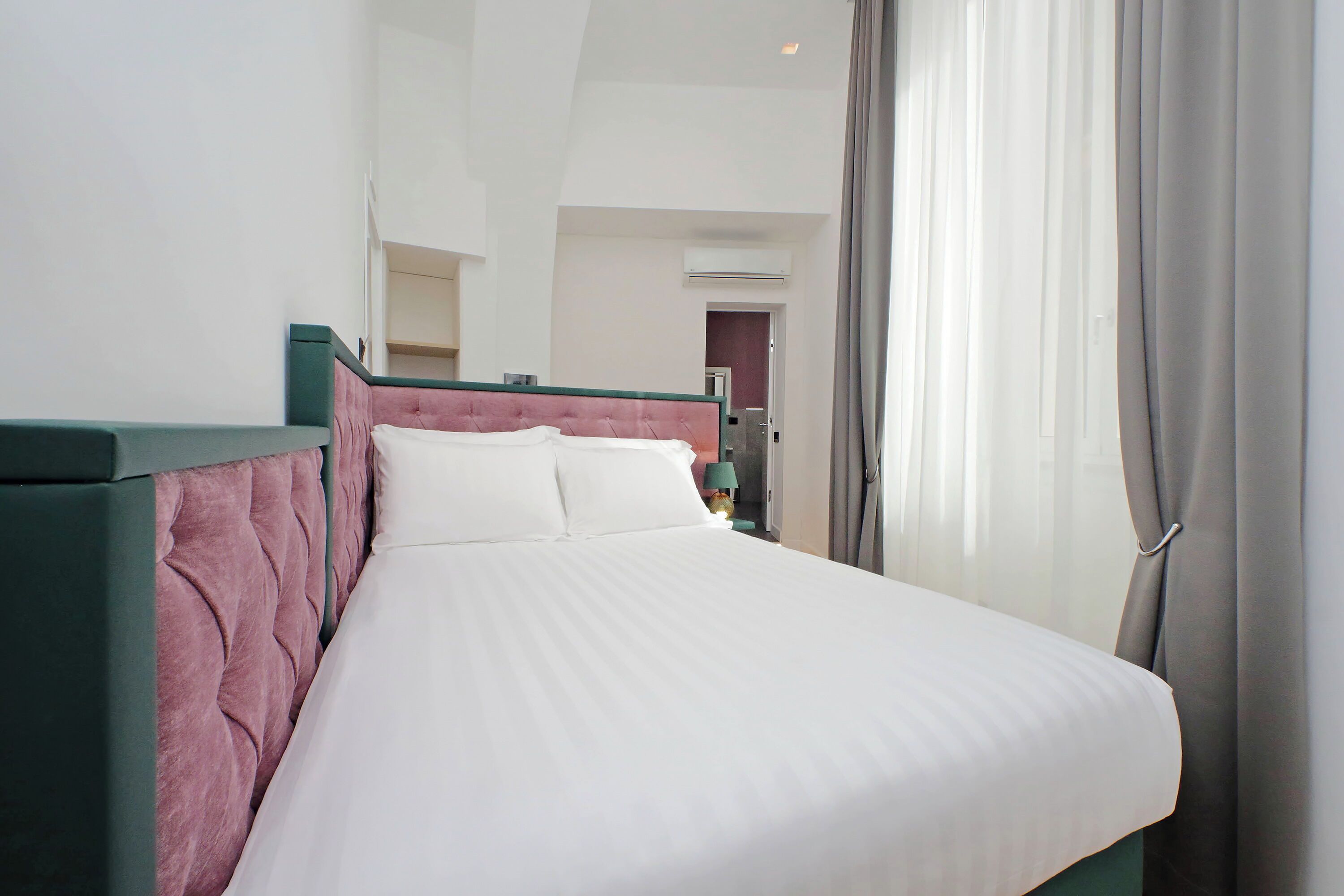 A neatly made bed with a green headboard and white bedding.