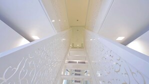 A modern interior with a central staircase flanked by decorative panels. - Domus Aurea Luxury Suites (Rome)