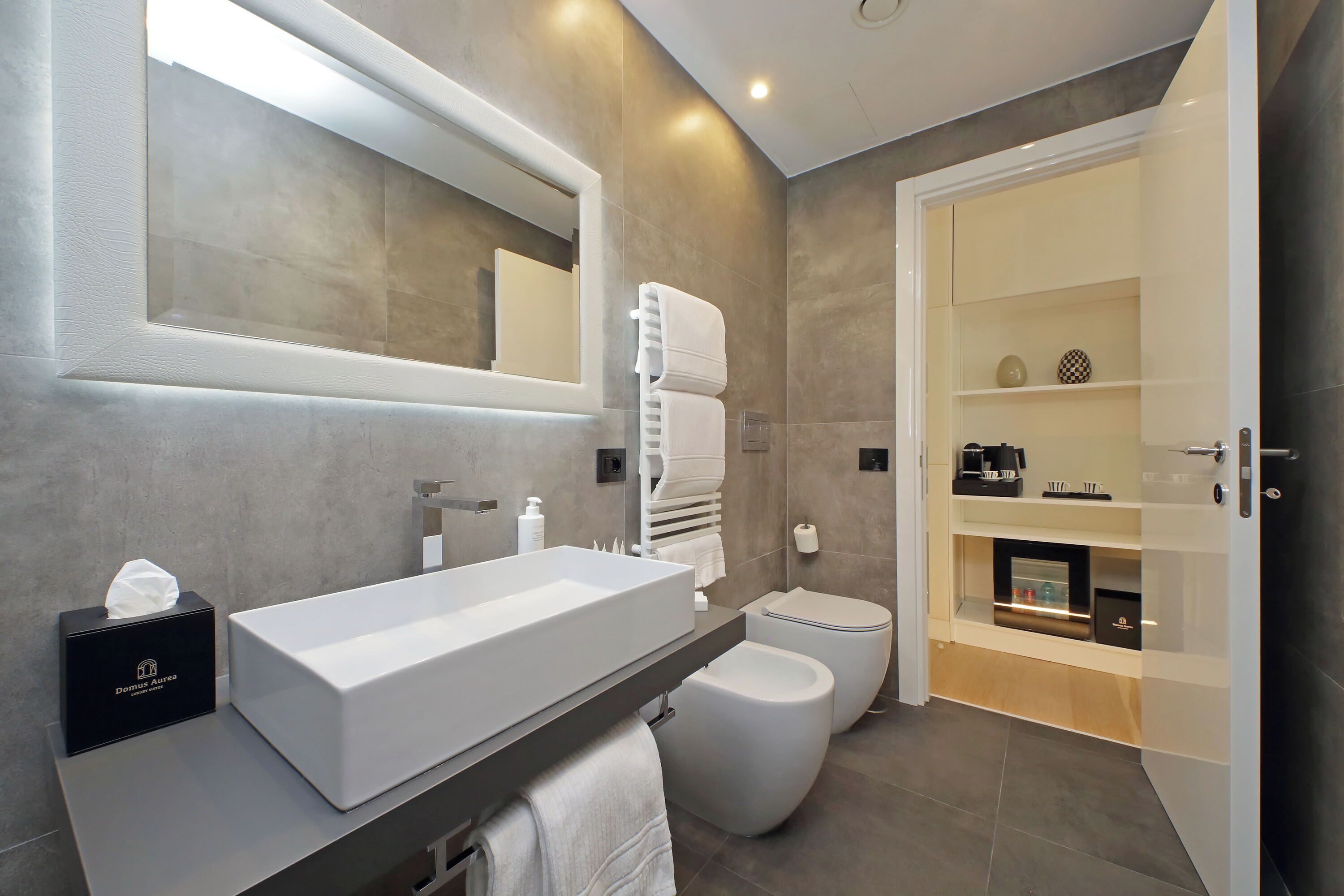 A modern bathroom with a large sink, toilet, and bidet, along with a vanity and storage cabinets.