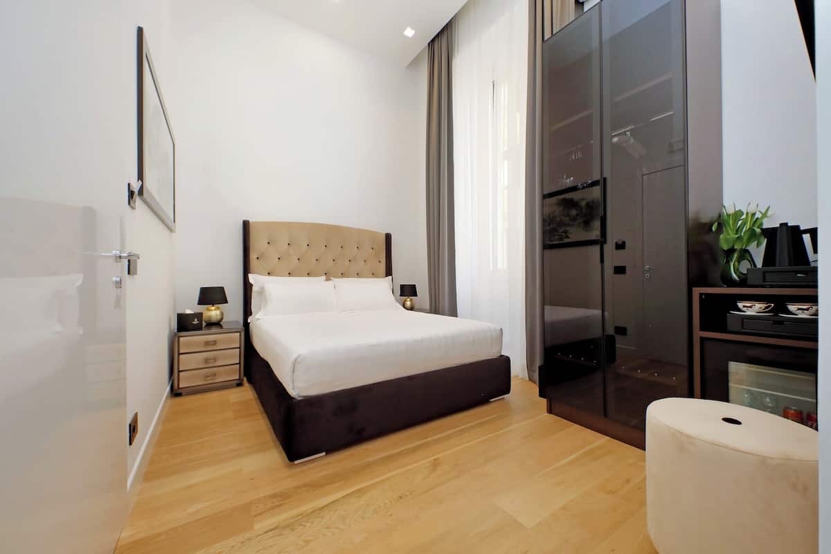 A modern bedroom with a large bed, a nightstand, a dresser, and a sliding glass door closet.