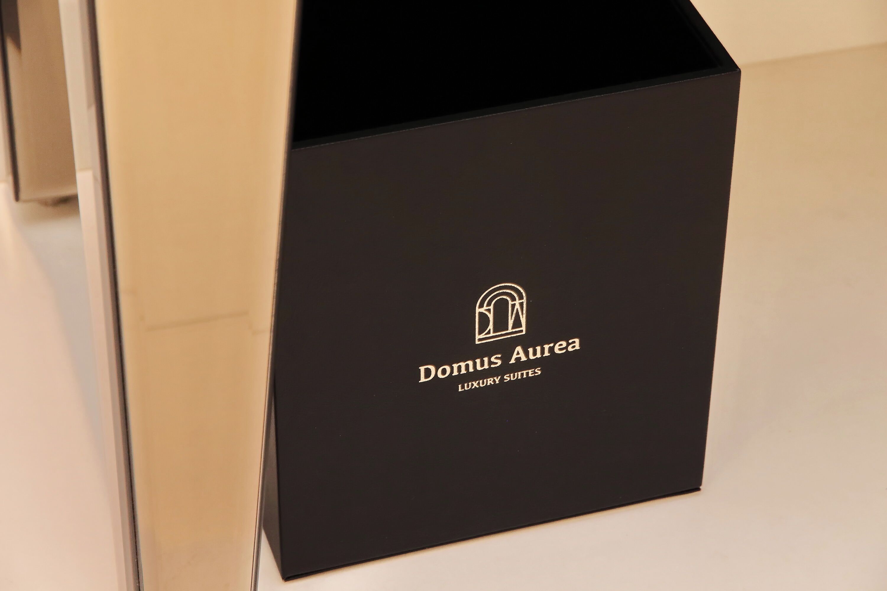 A black Domus Aurea Luxury Suites box with a logo and text.