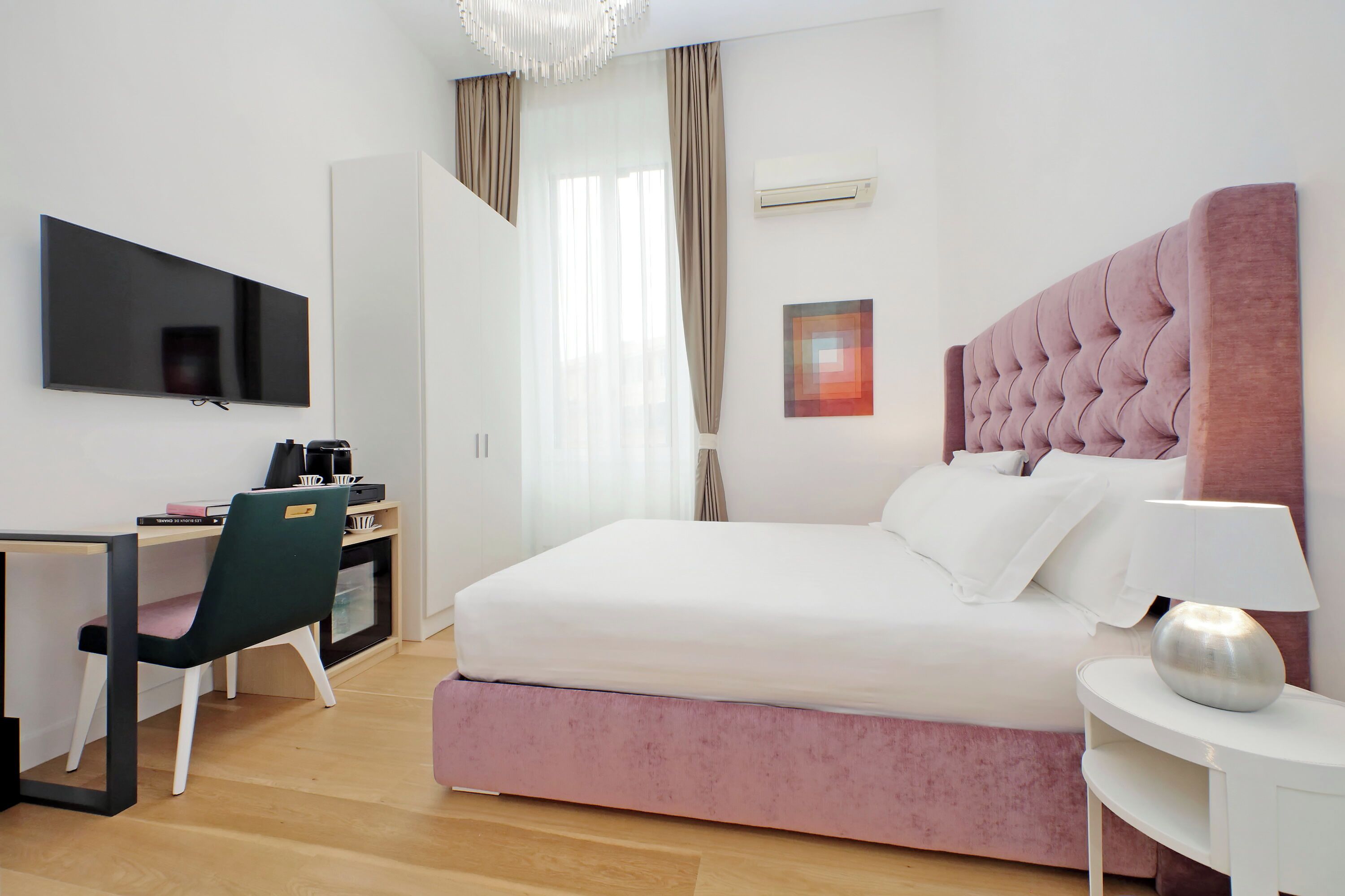 A modern bedroom with a large bed, a desk, and a TV.