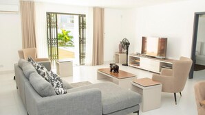 A modern living room with a grey sofa, a coffee table, and a TV stand. - 4 Bedroom Private Villa Villa La Tourelle (Tamarin)